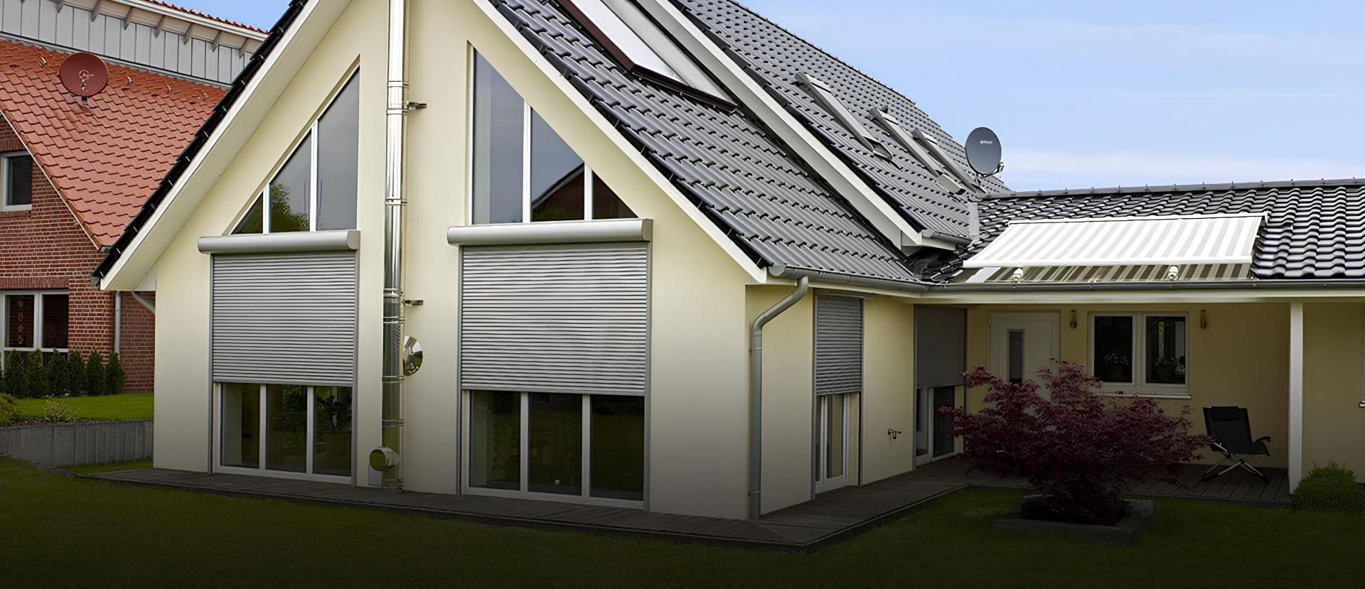 Ein hellgelbes Haus mit Außenrollläden